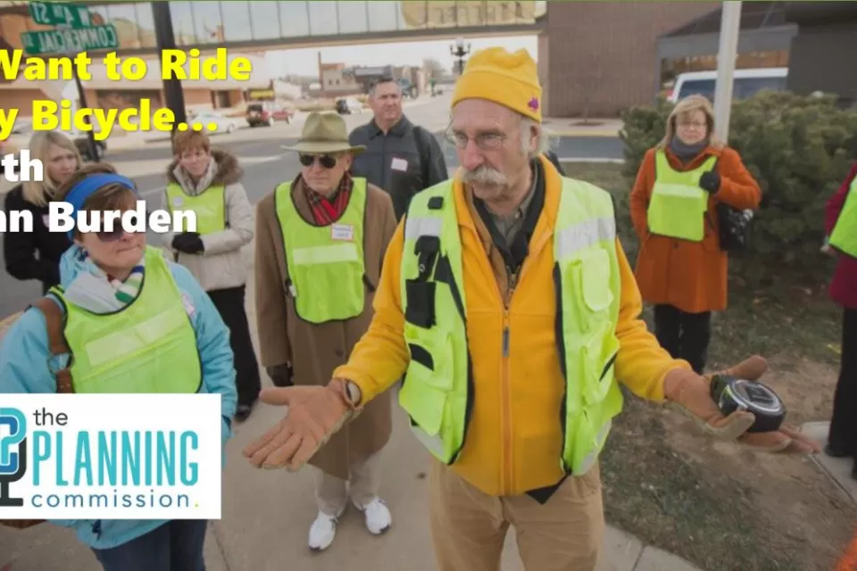 Graphic for The Planning Commission Podcast episode with photo of Dan Burden in safety vest speaking to crowd.